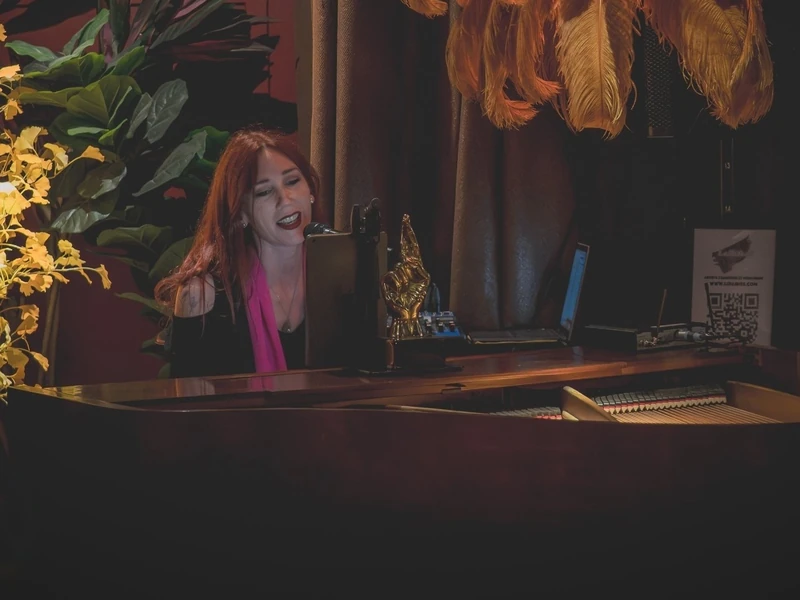 Lollirox chante et joue du piano à queue, sous une lampe en plumes, lors d’une soirée