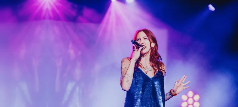 Lollirox chante sur scène, micro en main, dans les lumières d’un concert