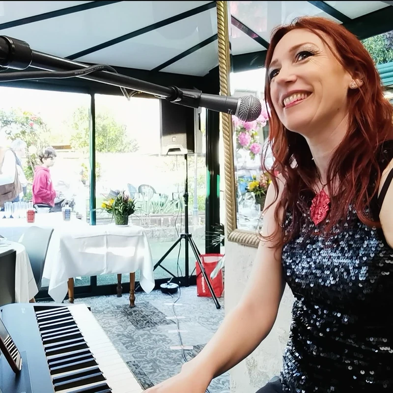 Lollirox souriante derrière son piano lors d’une prestation en terrasse